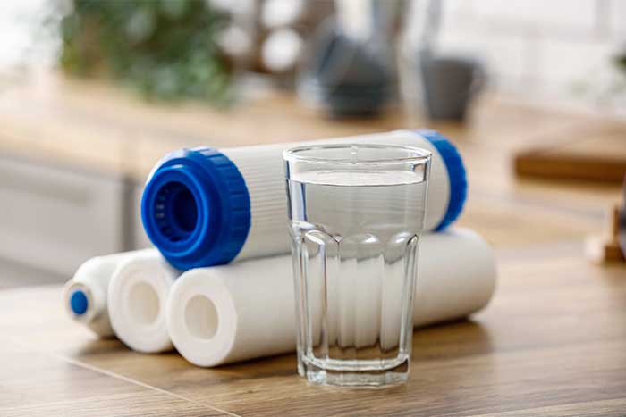 Glass of water with filters on wooden table Glass of water with filters on wooden table